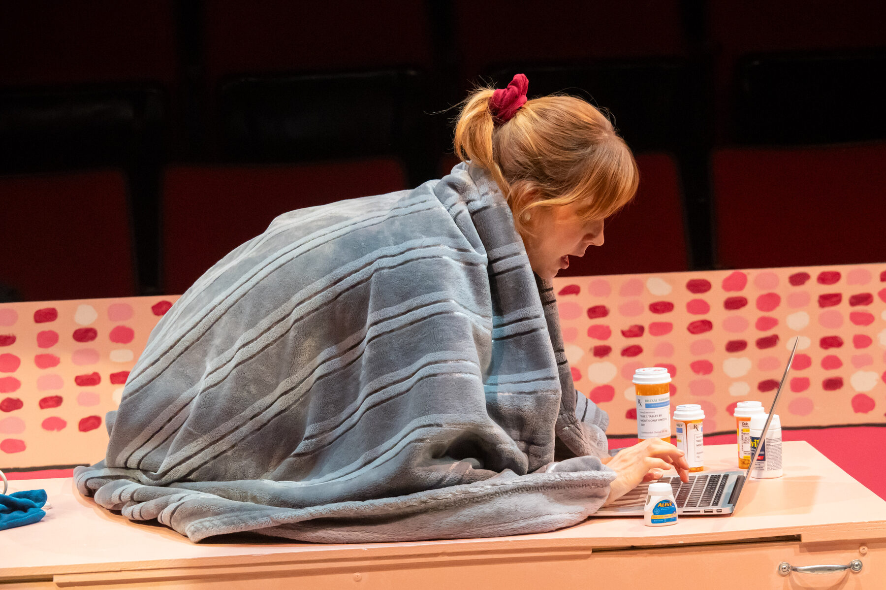 Lead under a blanket with pill bottles and laptop — illness in private