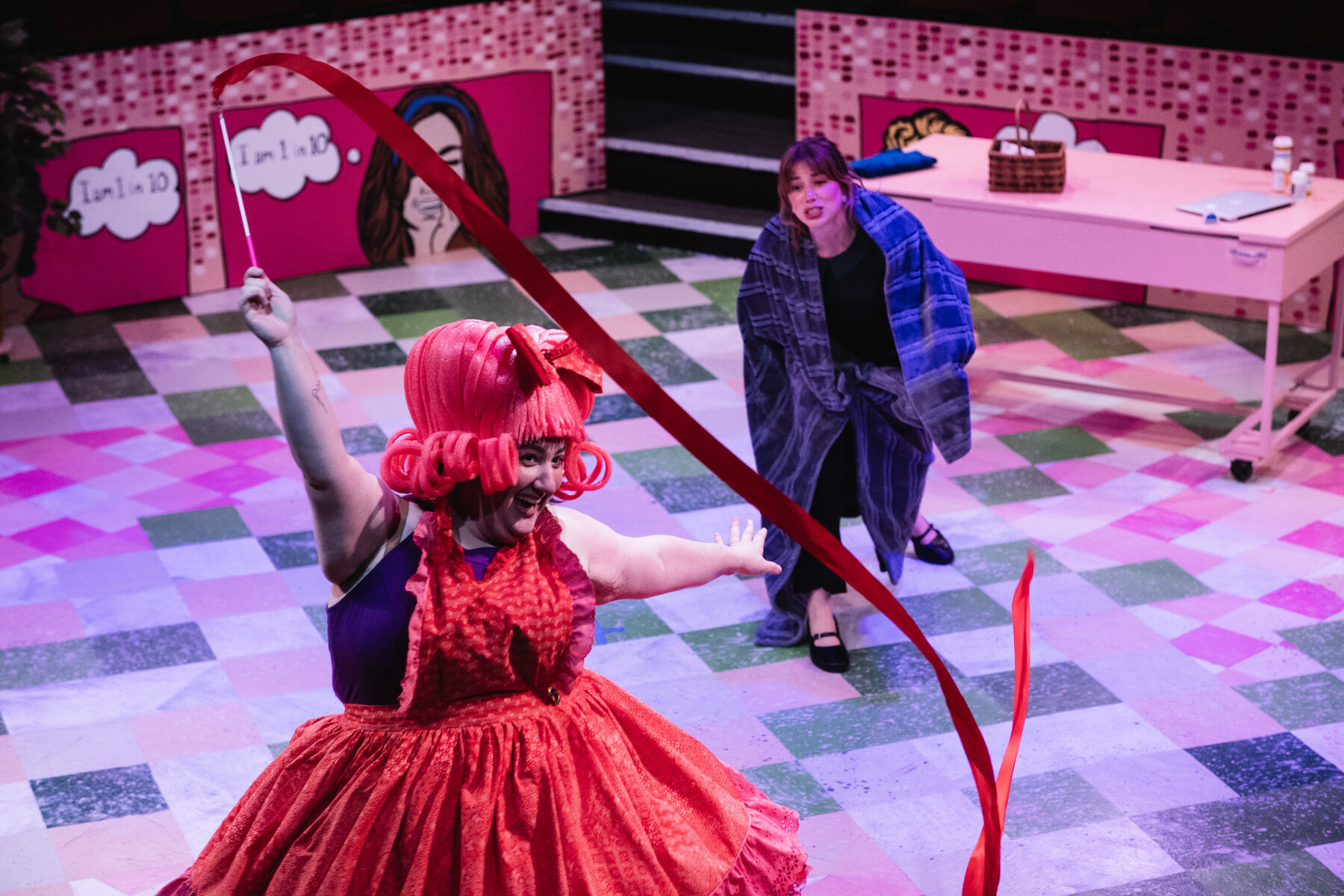Performer in a red dress with a red ribbon flying mid-air